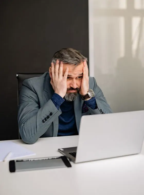A real estate agent reacting with alarm at his laptop after asking AI to shortlist local agents